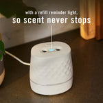 White Febreze Plug oil warmer on a countertop with a blue refill reminder light illuminated and copy about refill reminder.