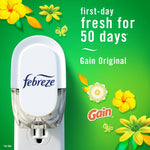 Close-up Febreze plug-in device on green background with text ‘first-day fresh for 50 days’ and Gain branding