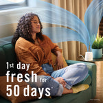 Woman relaxing on a couch while a Febreze PLUG warmer emits illustrated scent waves in a styled living-room scene.