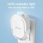 Febreze plug-in in an outlet against a blue wall with a glowing refill reminder light and explanatory text