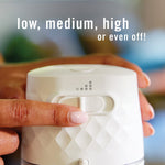 Close-up of a finger adjusting the control slider on a textured Febreze PLUG warmer with text about low, medium, high settings.