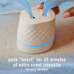 Top view of the Febreze Plug Scent Booster diffuser showing refill ports and illuminated blue ring with 'boost' usage text.