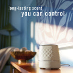 Febreze PLUG warmer on a table in a softly lit room with text highlighting long-lasting scent you can control.