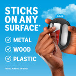 Hand peeling protective backing from Febreze Trash holder adhesive with text stating it sticks to metal, wood, and plastic