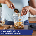Person filling a Hefty clear sandwich bag with trail mix over a counter to show expandable bottom and easy filling