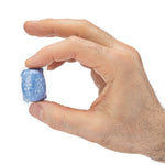 Close-up of fingers pinching a wrapped blue Dude Bombs pod against a white background