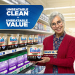Smiling older woman holding a Finish Ultimate Quantum pouch in a supermarket aisle with shelf display and value badge