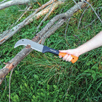 Hand holding a Fiskars curved brush axe cutting a small branch over grass and fallen wood
