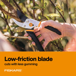 Person holding a Fiskars bypass pruner cutting through foliage with orange product banner at bottom