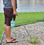 Person using a Flame King propane torch outdoors, handheld wand attached to a small green propane cylinder igniting a weed