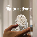 Hand flipping a white Febreze Bathroom device with large text instructing flip to activate