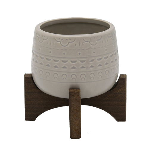 Matte grey Mayan-pattern ceramic planter on a small dark wooden stand, front view on white background.