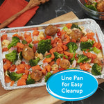 Baking sheet lined with foil holding roasted vegetables and potatoes on a countertop