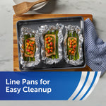 Three foil-lined pans on a baking sheet each holding salmon and asparagus, demonstrating lining pans with aluminum foil