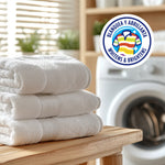 Stack of folded white towels on a wooden bench with washing machine and Ariel badge