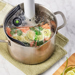 FoodSaver bag containing salmon and lime submerged in a pot of water with an immersion circulator for sous vide