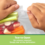 Close-up of hands tearing open a textured FoodSaver vacuum bag filled with cut vegetables, with 'Tear to Open' caption below