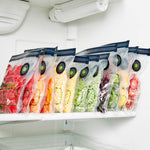 Row of FoodSaver reusable zipper bags filled with colorful frozen fruits and vegetables in a freezer shelf