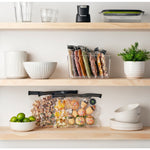 Shelves displaying FoodSaver vacuum bags filled with various foods alongside kitchen containers and decor