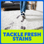 Person walking across a white shag rug leaving dark footprints with bright banner reading “TACKLE FRESH STAINS”