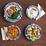 Four Dixie Ultra blue patterned paper bowls displayed with different meals on a wooden table setting