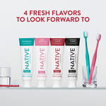 Four Native toothpaste tubes in different flavors lined up on a shelf with two toothbrushes in a glass at the right