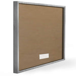 Rear view of a framed print showing the cardboard backing and silver frame edge at an angle.
