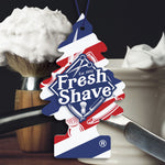 Close-up lifestyle image of Fresh Shave Little Trees air freshener hanging in front of shaving brush and bowl