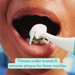 Open mouth with metal braces while a teal-and-white electric flosser head cleans under the wires.