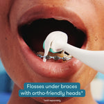 Close-up of a person with braces using a mint Frida flosser head under the archwire with on-image braces-friendly text