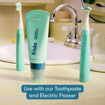 Lifestyle sink scene with mint Frida electric toothbrushes and matching Frida fluoride toothpaste tube on countertop