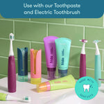Bathroom countertop scene showing Frida toothpaste tubes, toothbrushes, chargers and flosser heads arranged with branded badge