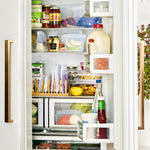 Open refrigerator shelf stocked with foods stored in Stasher reusable bags and round silicone stretch lids