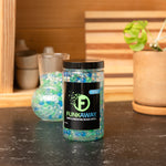 Styled kitchen scene with a FunkAway jar of blue and green odor-eliminating beads on a countertop and a vase behind it.