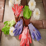 Assorted G & F garden gloves arranged with flowers and terracotta pots on a paved surface in a lifestyle display