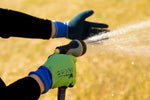 Person wearing G & F lime green and navy gardening gloves holding a watering hose nozzle