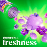 Gain bottle spilling purple scent beads turning into glossy purple droplets and flowers on a radiant green background.
