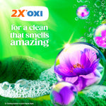 Green advertising graphic with '2X OXI' claim and purple flower inside a soap-bubble over foam and fabric texture