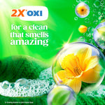Close-up promotional art of a yellow flower inside a soap bubble with '2X OXI' claim and green bubbly background