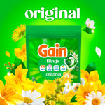 Green pouch of Gain Flings Original shown among yellow and white flowers on a vivid green background