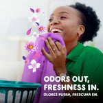 Person smelling a purple towel with floating floral scent graphics and text about odors out, freshness in