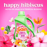 Gain Happy Hibiscus fabric softener bottle amid colorful tropical flowers with 'happy hibiscus' and scent notes text on pink background