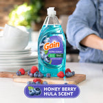 Bottle of Gain Ultra Clean Honey Berry Hula dish soap on a countertop with berries and stacked dishes in a kitchen setting
