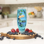 Upside-down blue Gain Ultra Clean EZ‑Squeeze bottle placed on a wooden board surrounded by blueberries and strawberries in a kitchen
