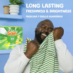 Lifestyle shot of a person happily smelling laundry with Gain powder box and 'long lasting freshness & brightness' text