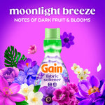 Gain Moonlight Breeze bottle centered among assorted purple and white flowers on magenta background