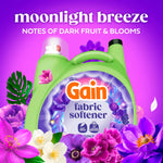 Gain fabric softener jug centered among purple and white flowers with ‘moonlight breeze’ scent name prominently displayed above