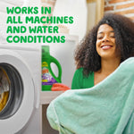 Lifestyle image of a smiling person by a washing machine with a Gain Moonlight Breeze detergent bottle visible on a shelf and text 'WORKS IN ALL MACHINES AND WATER CONDITIONS'.