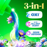 Pouring detergent stream over flowers with 3-in-1 benefit icons listing OXI, up to all day scent, and odor defense on green background