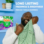 Smiling person holding a striped shirt next to a Gain powder Moonlight Breeze package and text about long lasting freshness